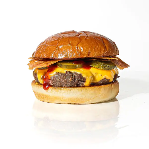 Cheeseburger with melted American cheese, pickles, ketchup, and crispy bacon strips on a toasted bun, Chivuo's