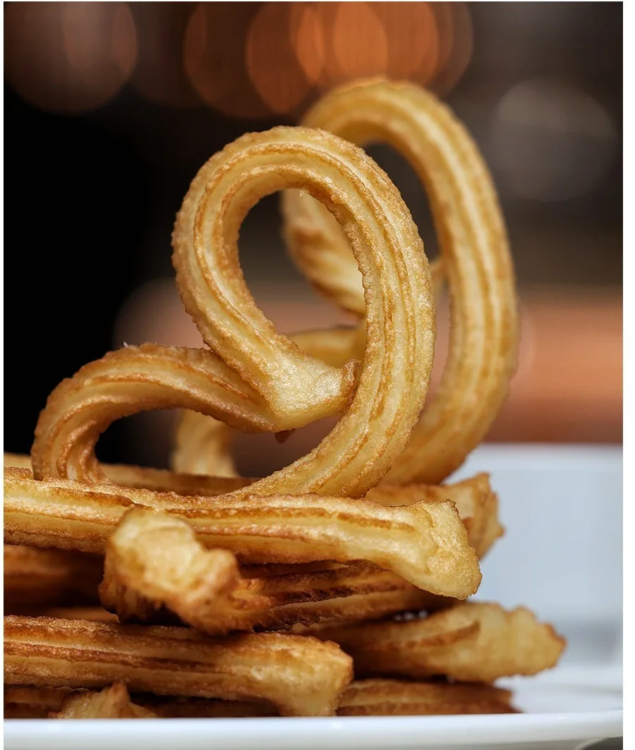 A looped golden churro on top of a pile of churros