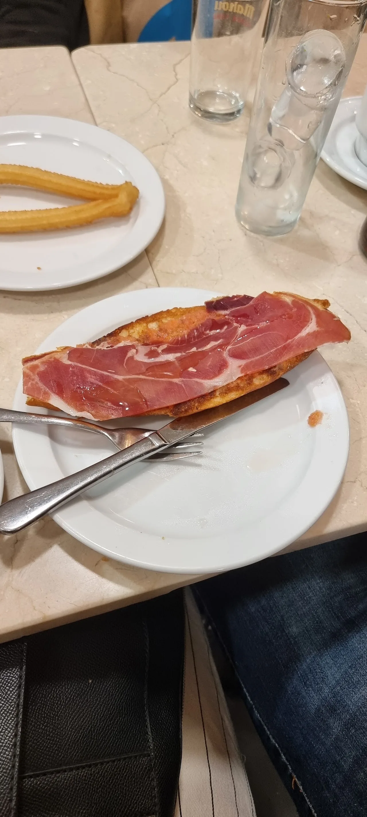 A plate of jamon iberico slices next to a cup of churros