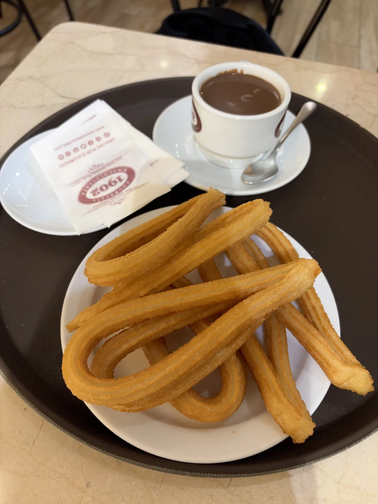 A plate of churros with a cup of hot chocolate for dipping