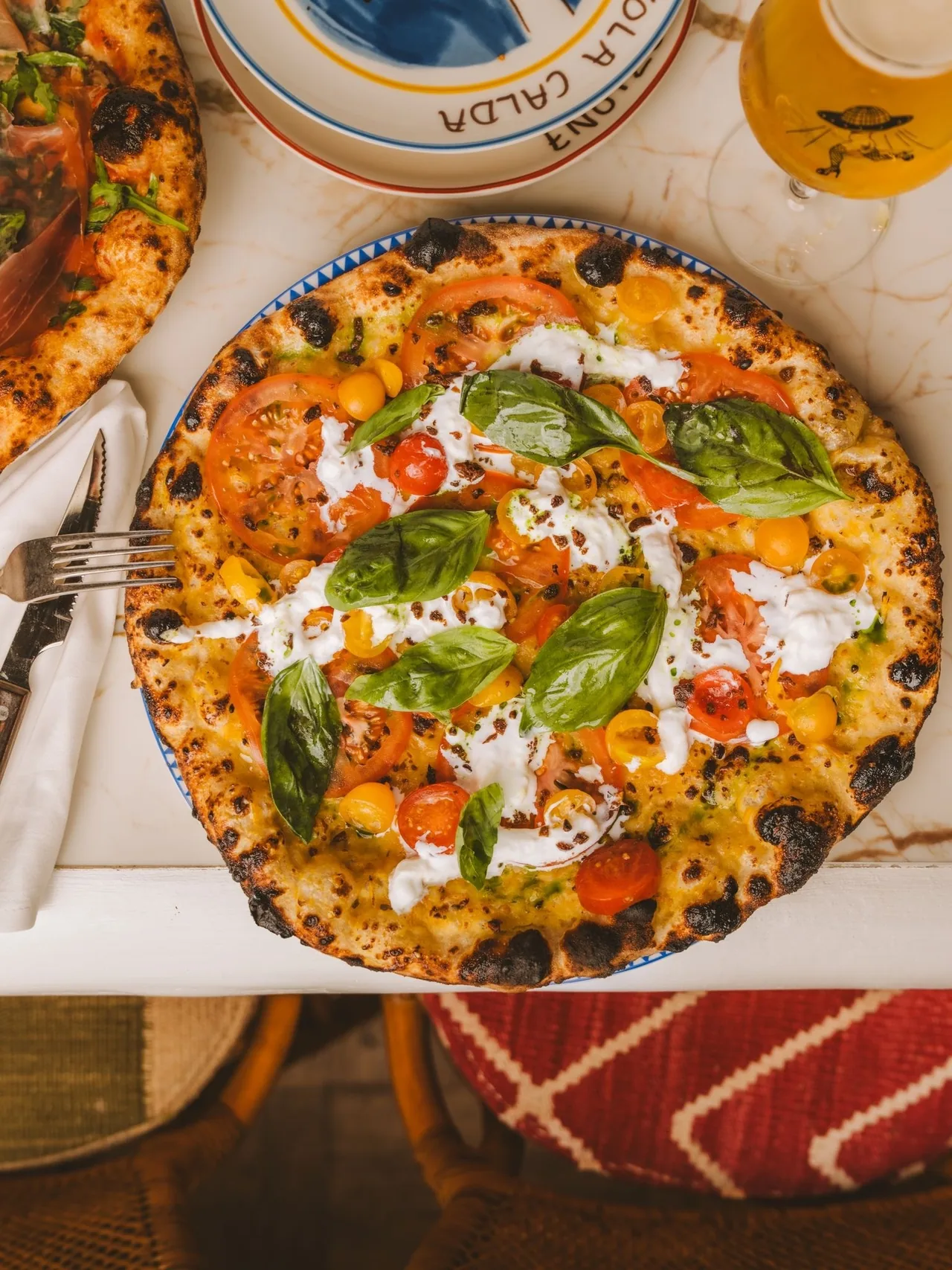 A baked pizza with tomato, white cheese and basil leaves seen from above