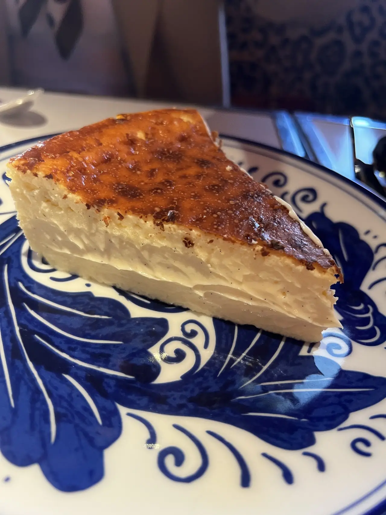 A slice of baked cheesecake-style tart on a blue-and-white patterned plate.