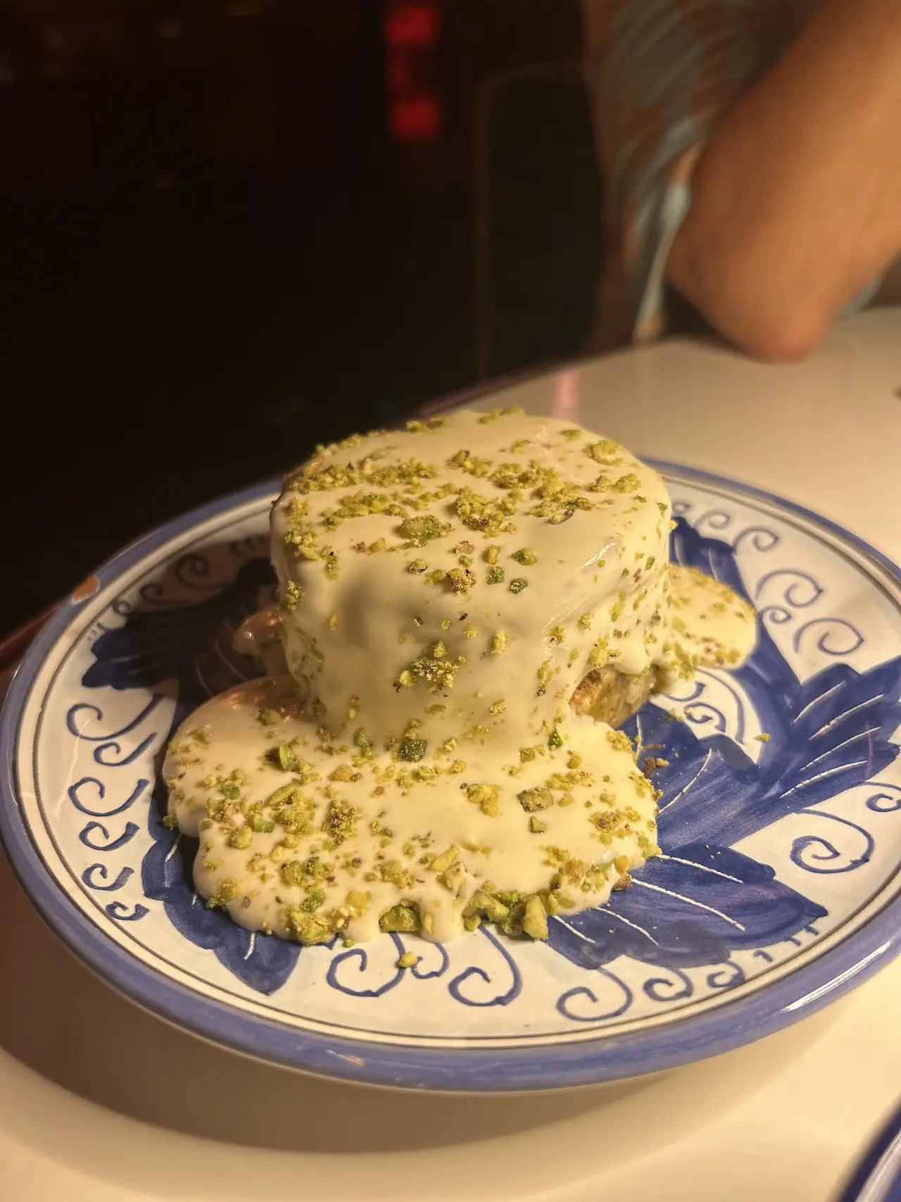 A quenelle-shaped mound dusted with green crumbs on a blue-and-white plate