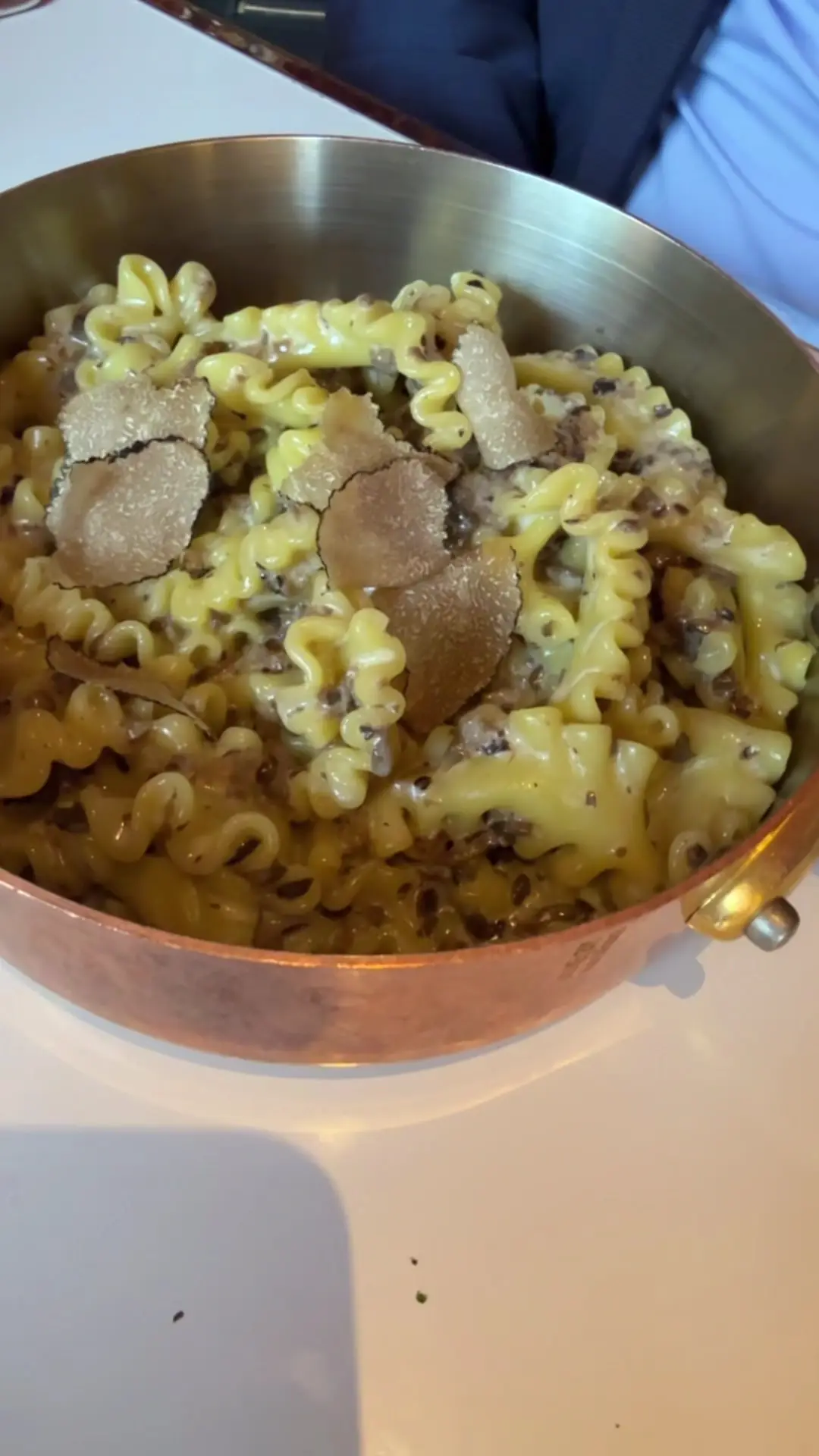 A copper pot of pasta tossed with shaved black truffle.