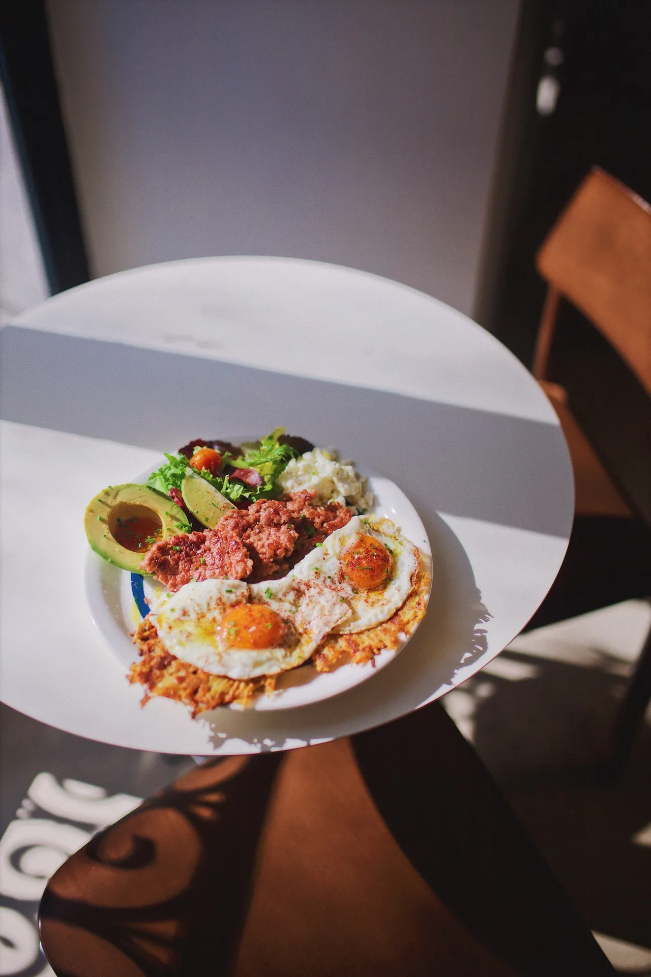 A plate of fried eggs, avocado and a savoury meat mixture seen from above