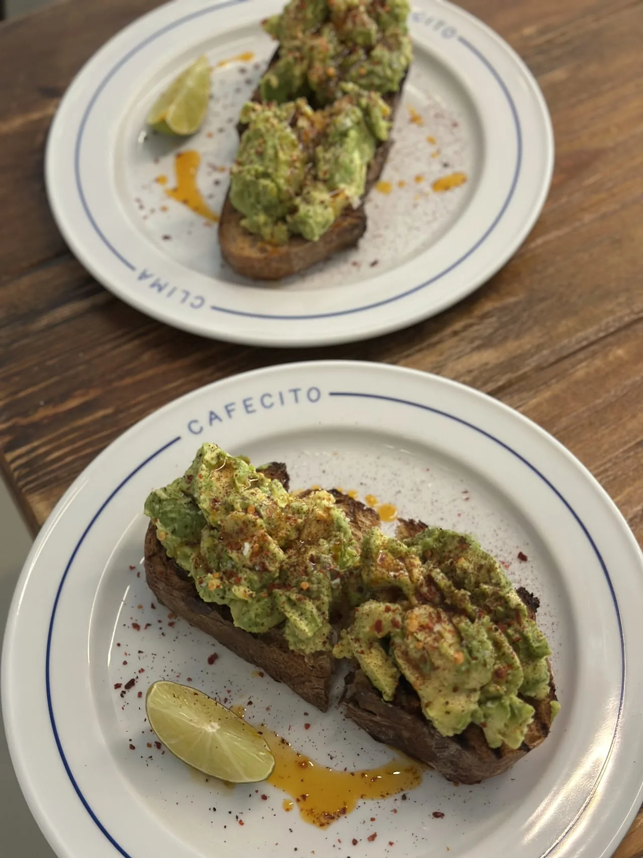 Two plates of avocado toast on marble-patterned dishes