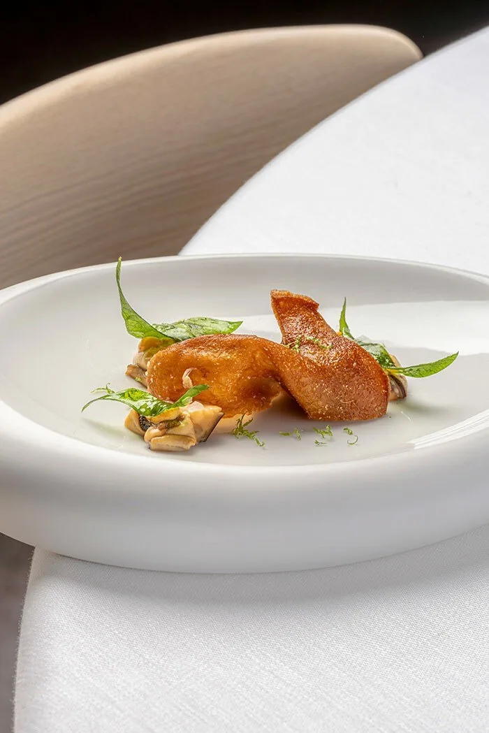 A small roasted bird portion with herbs on a wide white plate
