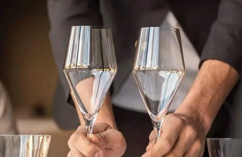 Server placing two poured glasses of sparkling wine on the table