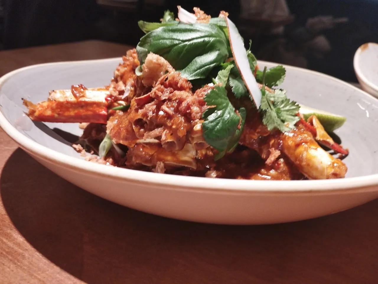 A curry dish with shellfish, herbs, and crispy shallots