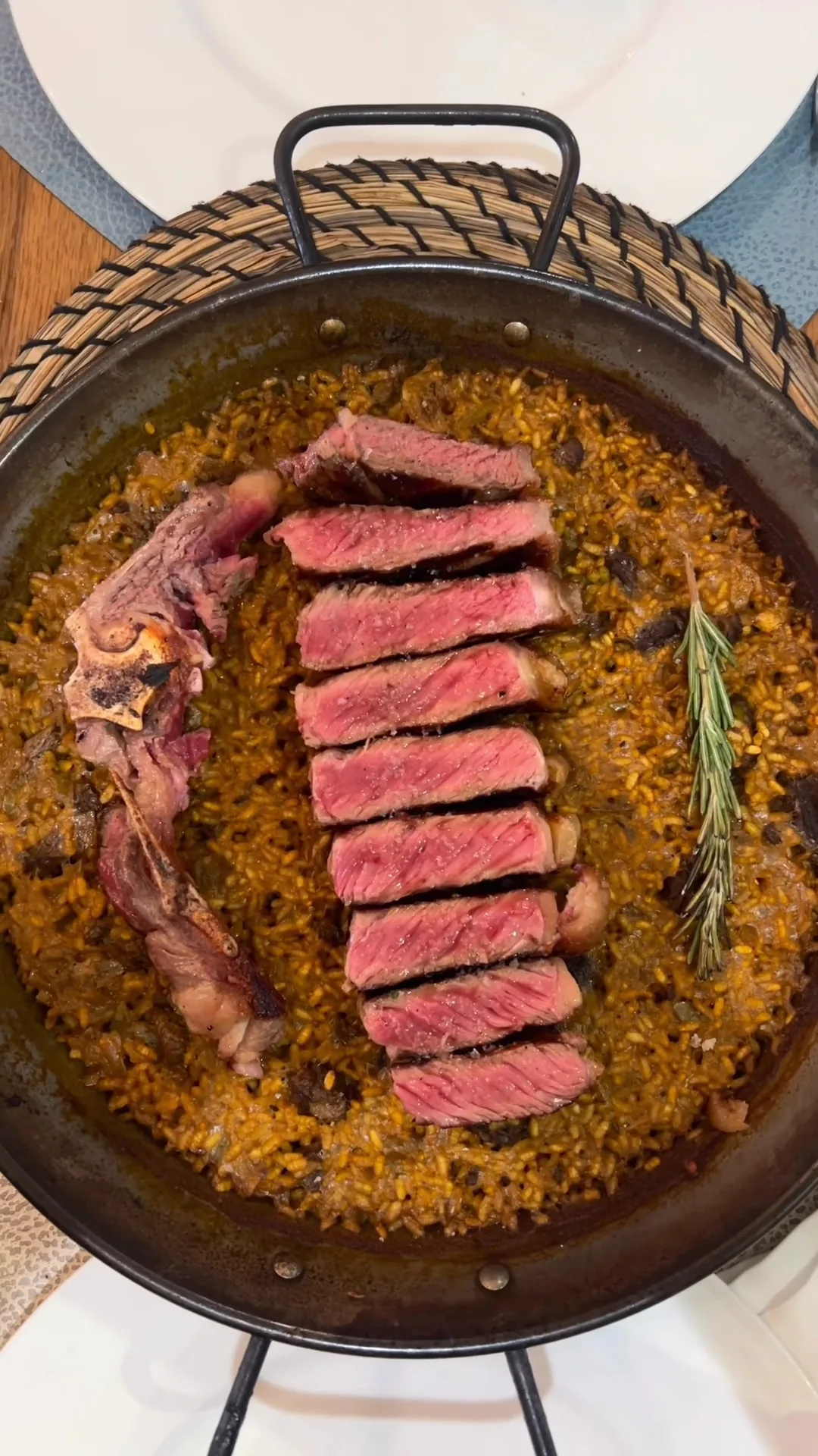 Sliced seared steak arranged in a paella-style pan