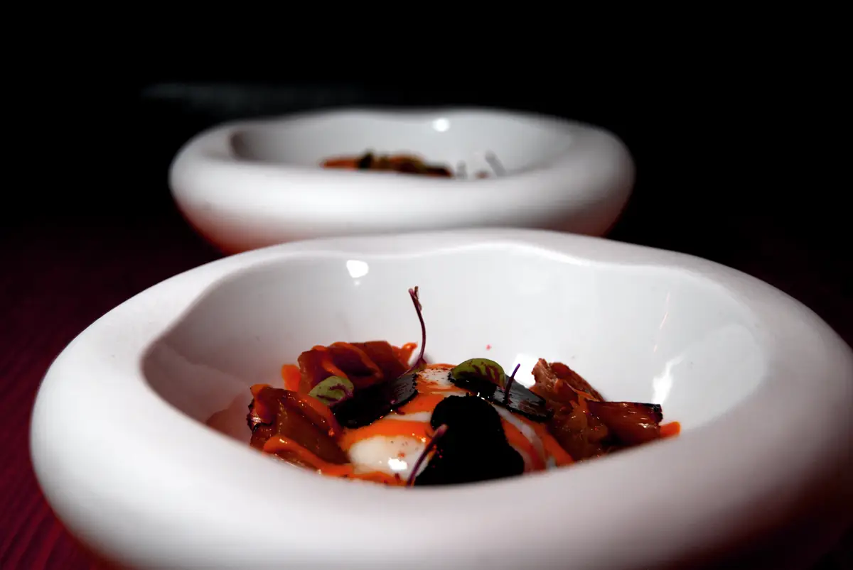 Seared fish fillet with dill, potato puree, and a tikka-style sauce dollop on a charred black plate, Con Gracia