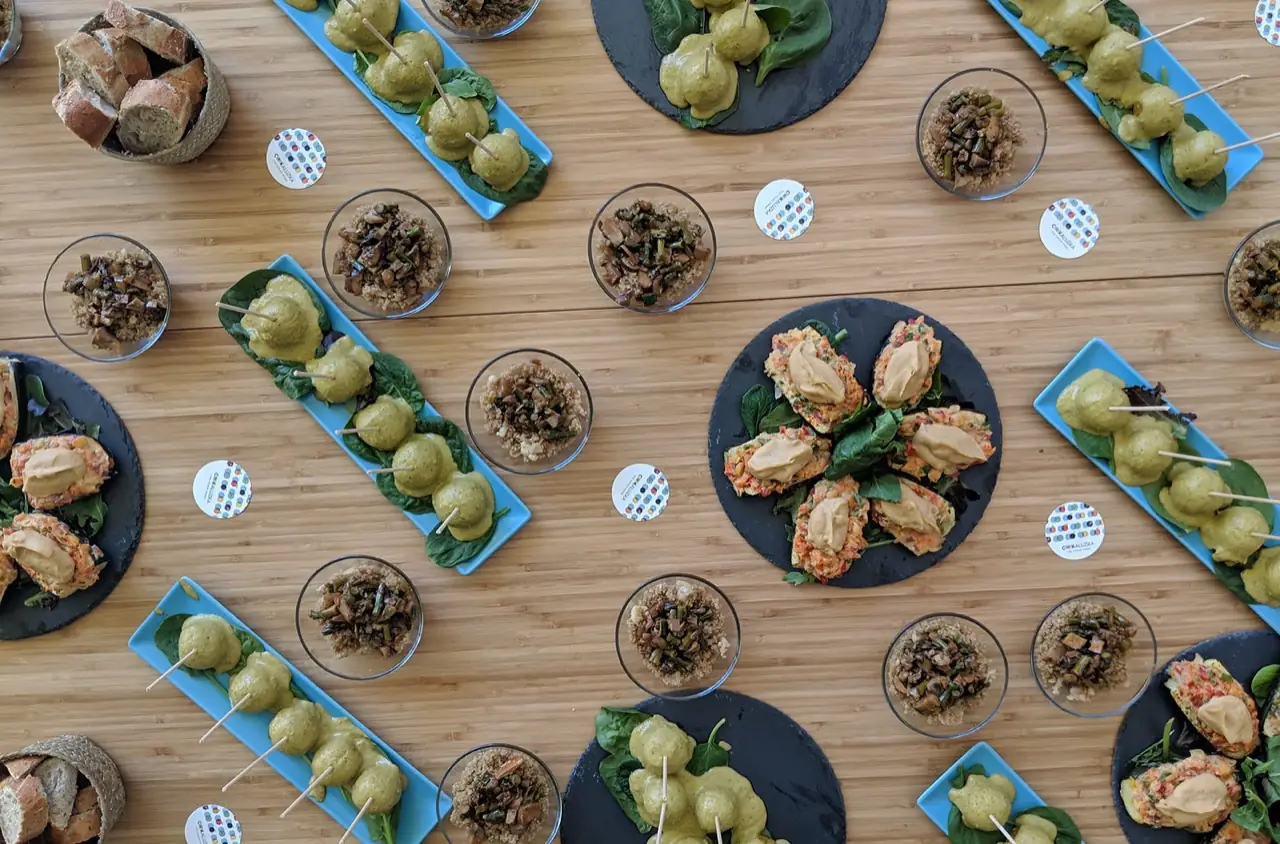 Skewered vegetarian bites with green sauce, mushroom-quinoa cups and stuffed avocado halves on slate boards