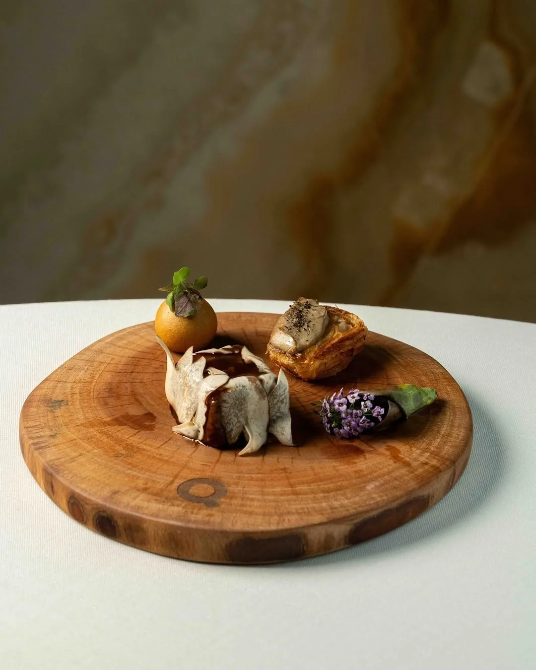 Small bites arranged on a round wooden board on a white table
