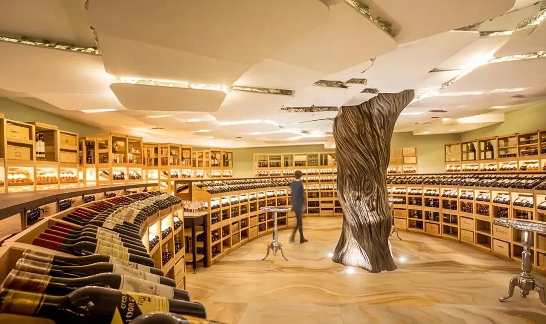 A circular wine cellar with curved racks of bottles around a sculpted central column