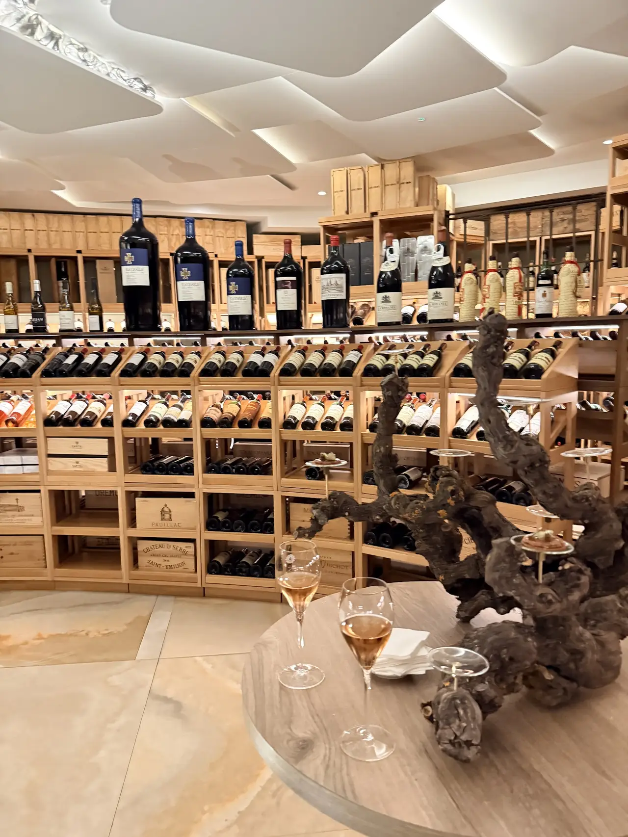 Two glasses of poured wine on a table in front of the restaurant wine cellar shelving