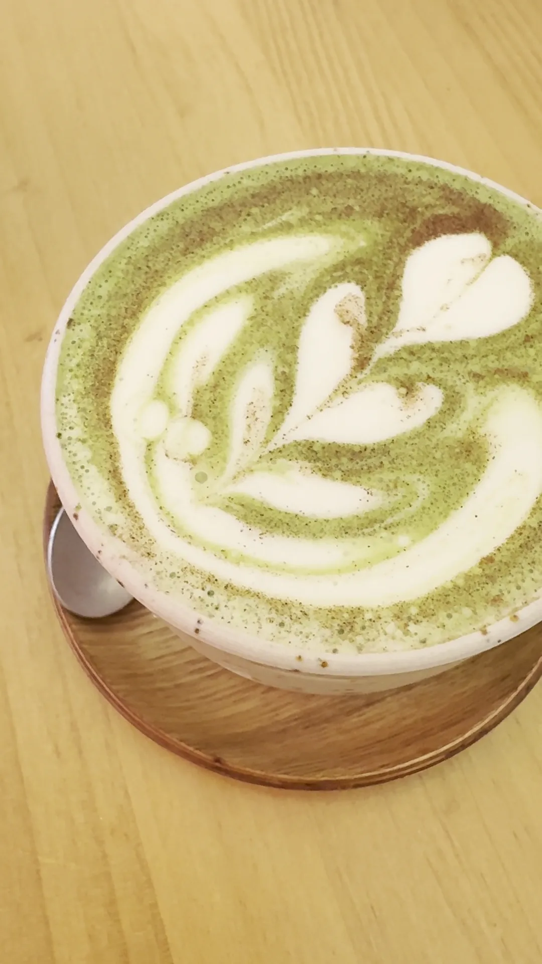 A matcha latte with delicate leaf-pattern foam art, seen from above