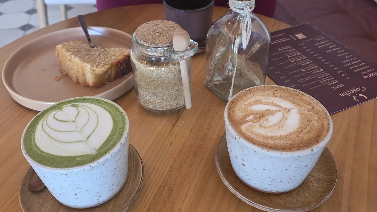 A matcha latte and a regular latte served together on a wooden table
