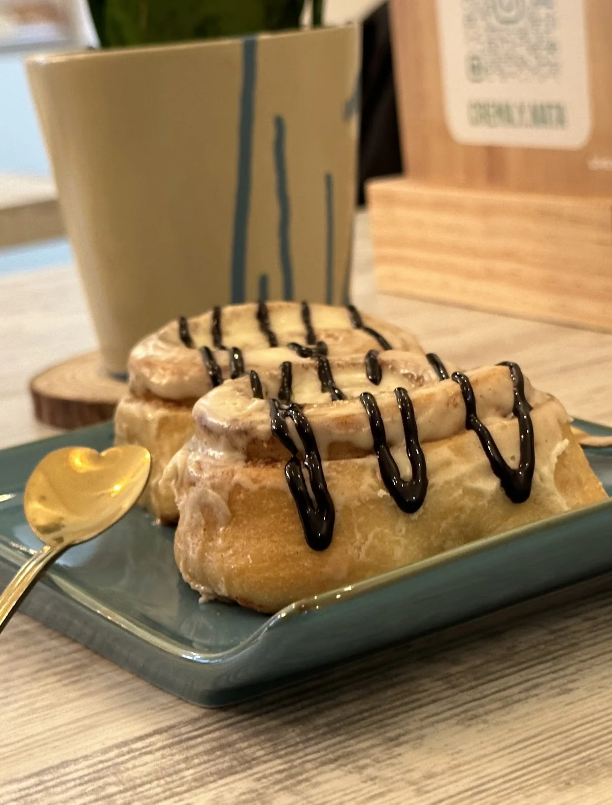 Two cinnamon rolls drizzled with chocolate sauce on a plate