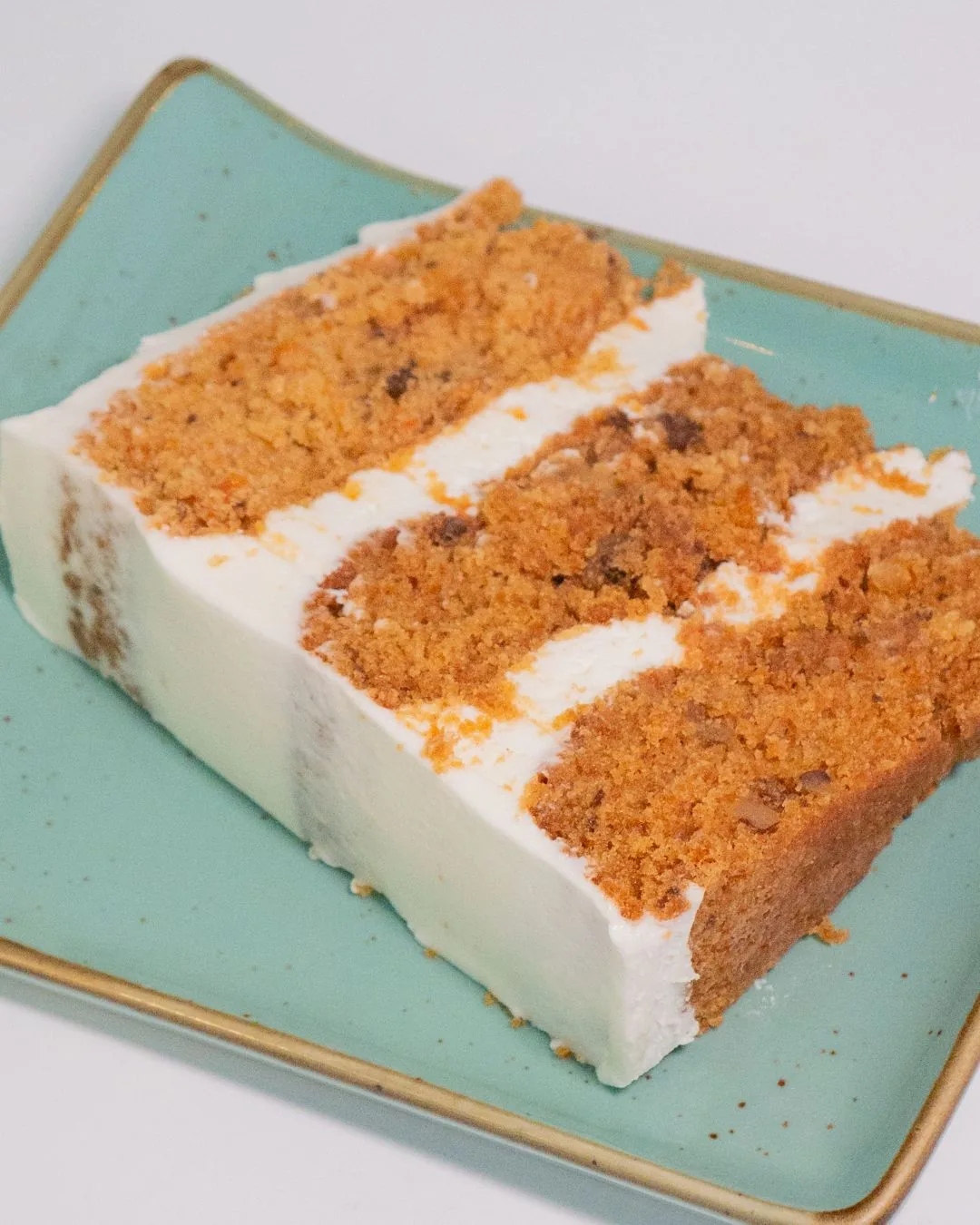A slice of carrot layer cake on a teal plate