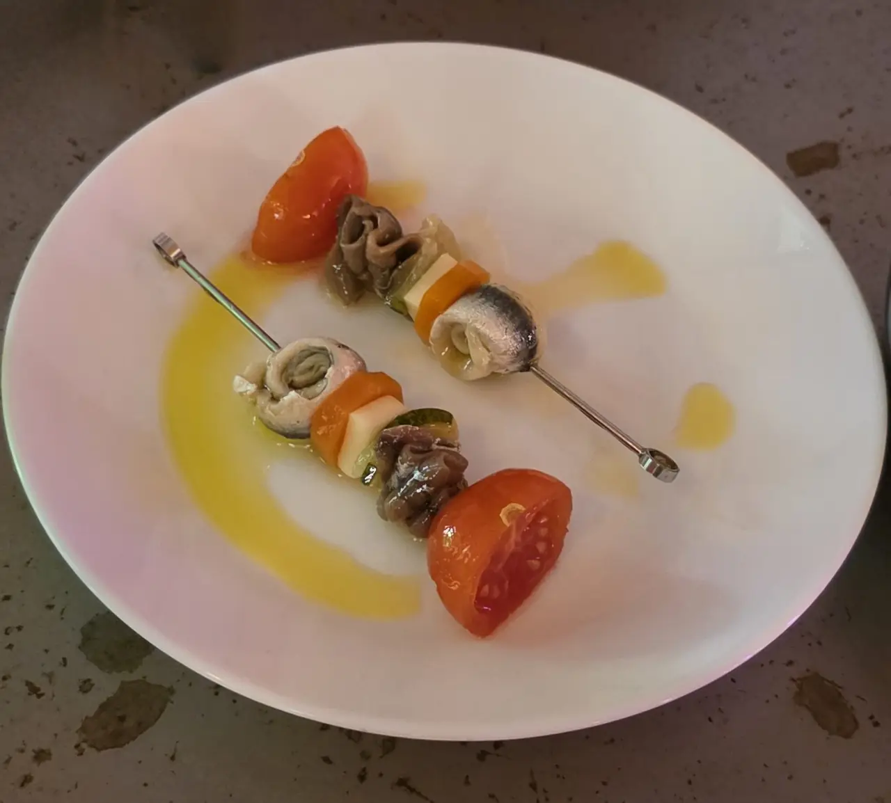 Two gilda-style skewers with anchovy and vegetables in olive oil