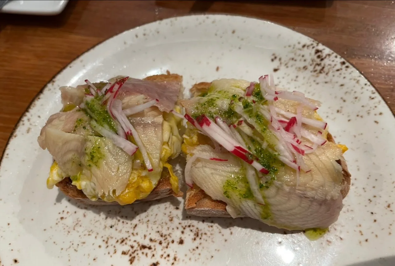 Two toasts topped with cured fish and radish