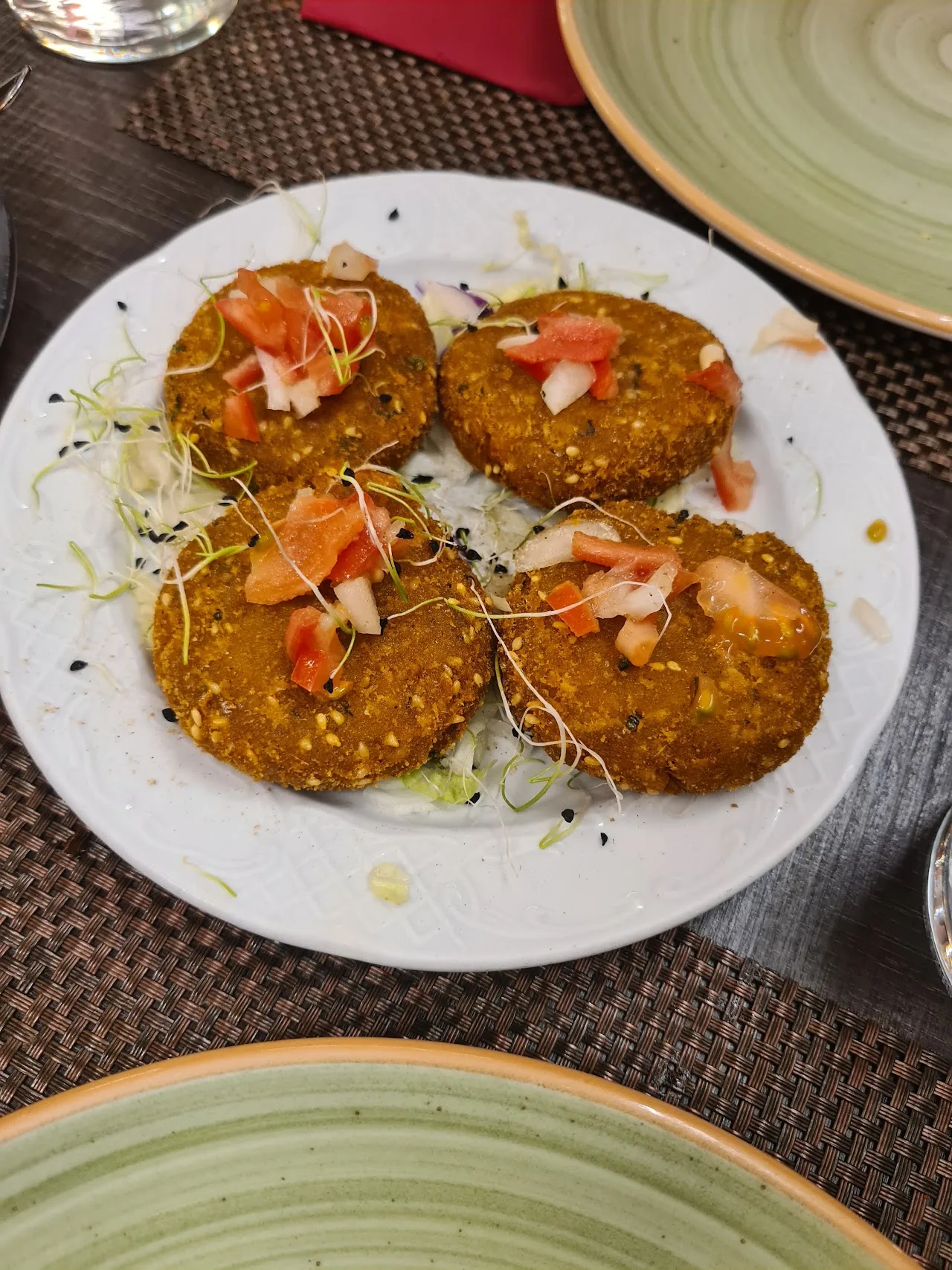 Four spiced fritters garnished with herbs on a plate