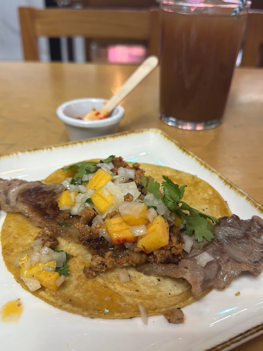 A taco topped with diced mango, onion, and cilantro