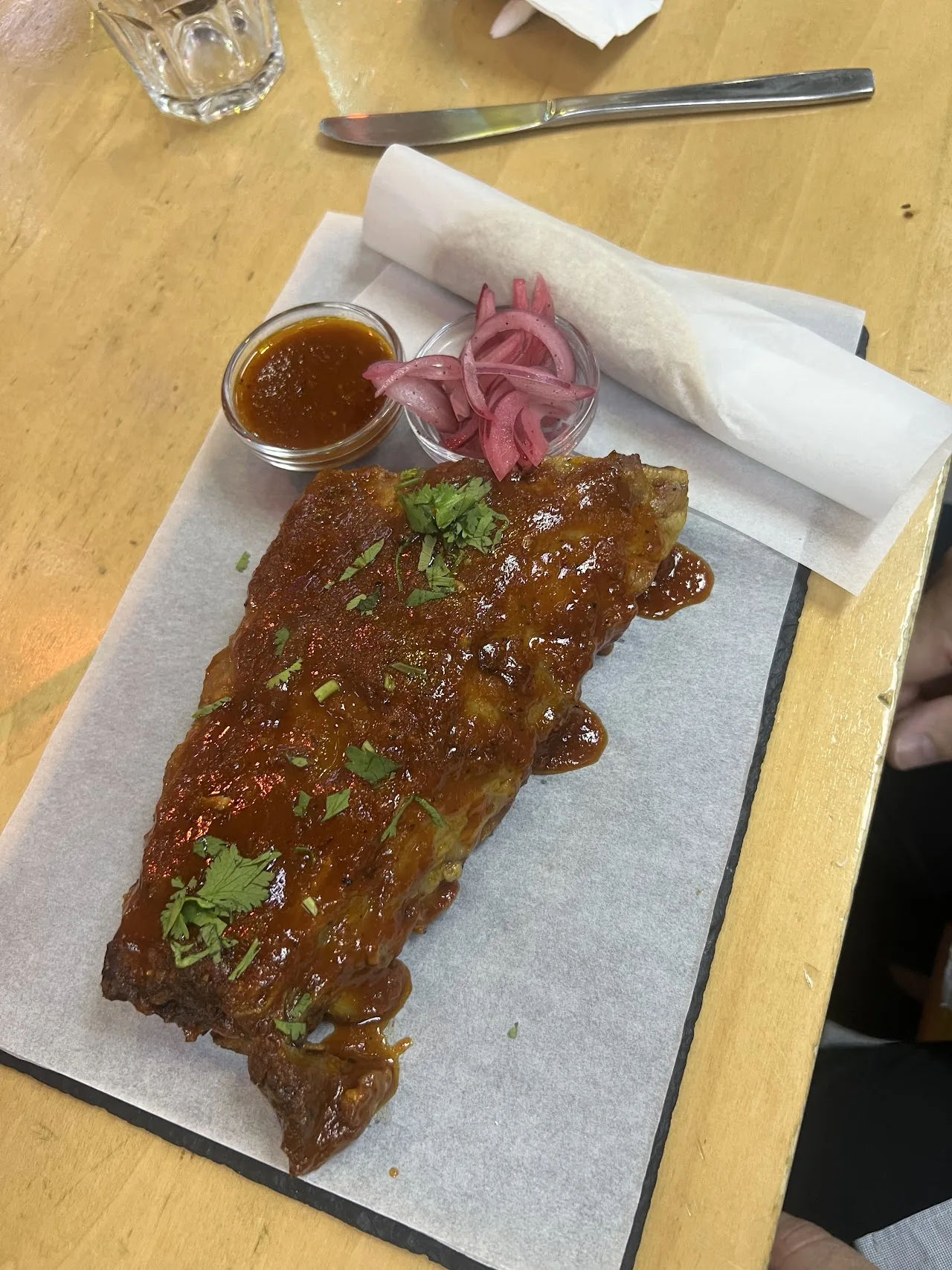 Barbecue ribs on paper, garnished with pickled red onion