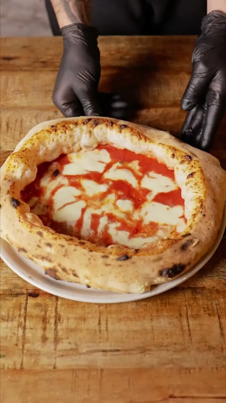 Neapolitan Margherita pizza with a puffy charred crust, melted mozzarella and tomato sauce on a white plate, Pizzeria Da Nanni Llibreteria
