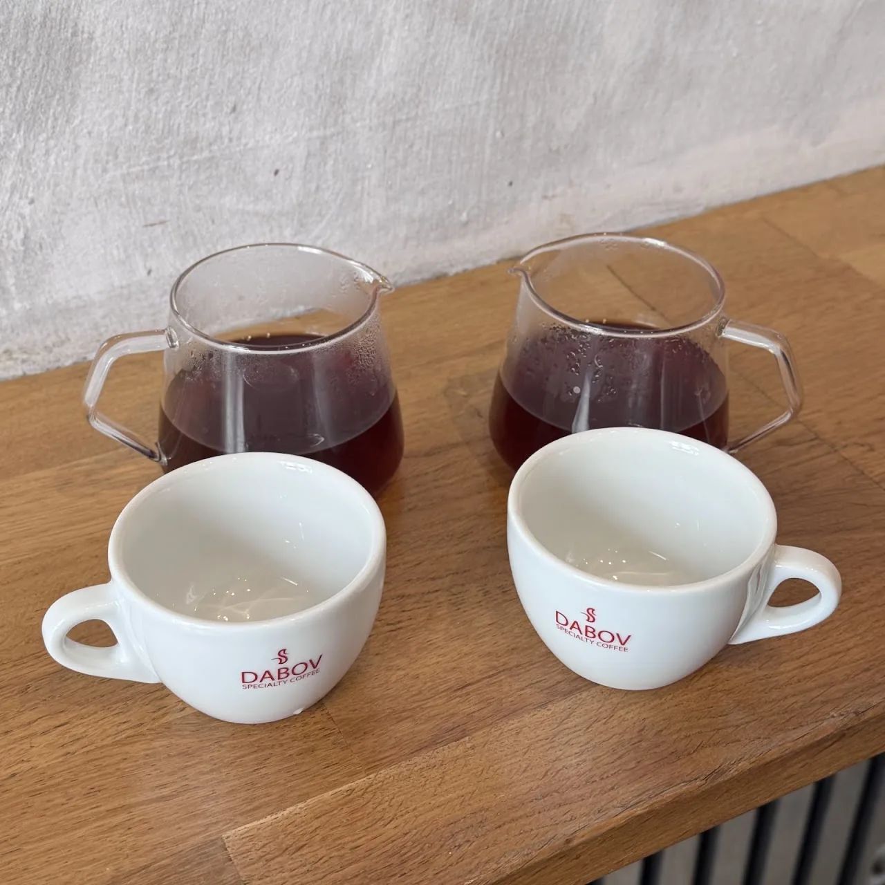 Two glass carafes of pour-over coffee beside small cups