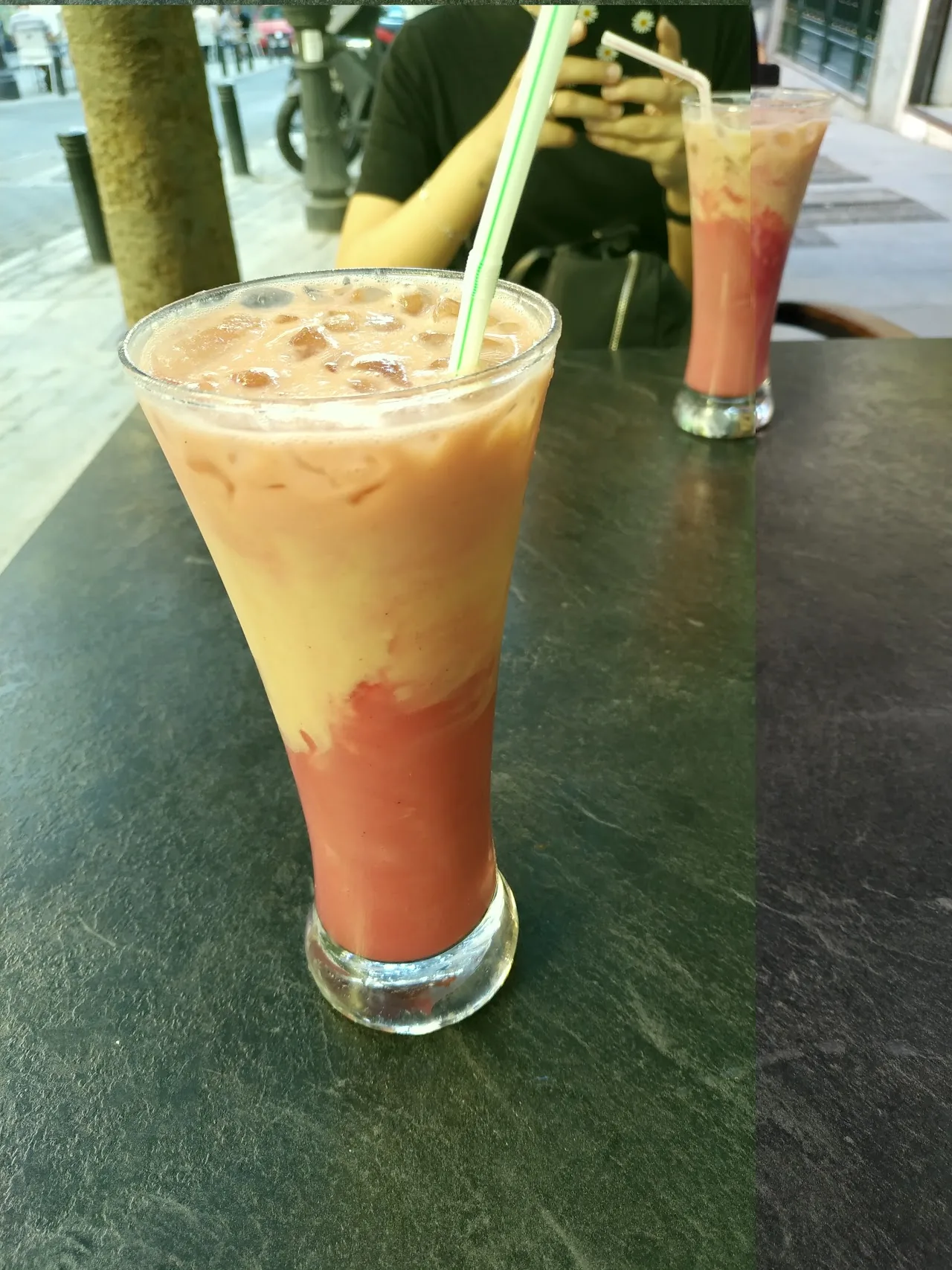 Two fruit smoothies with straws on an outdoor table