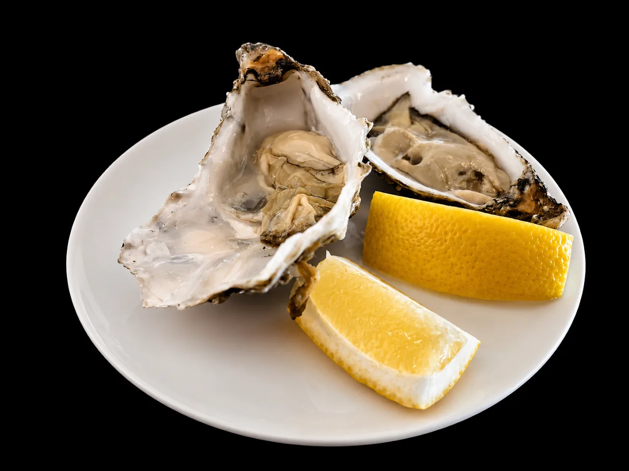 A plate of oysters on the half shell with lemon wedges