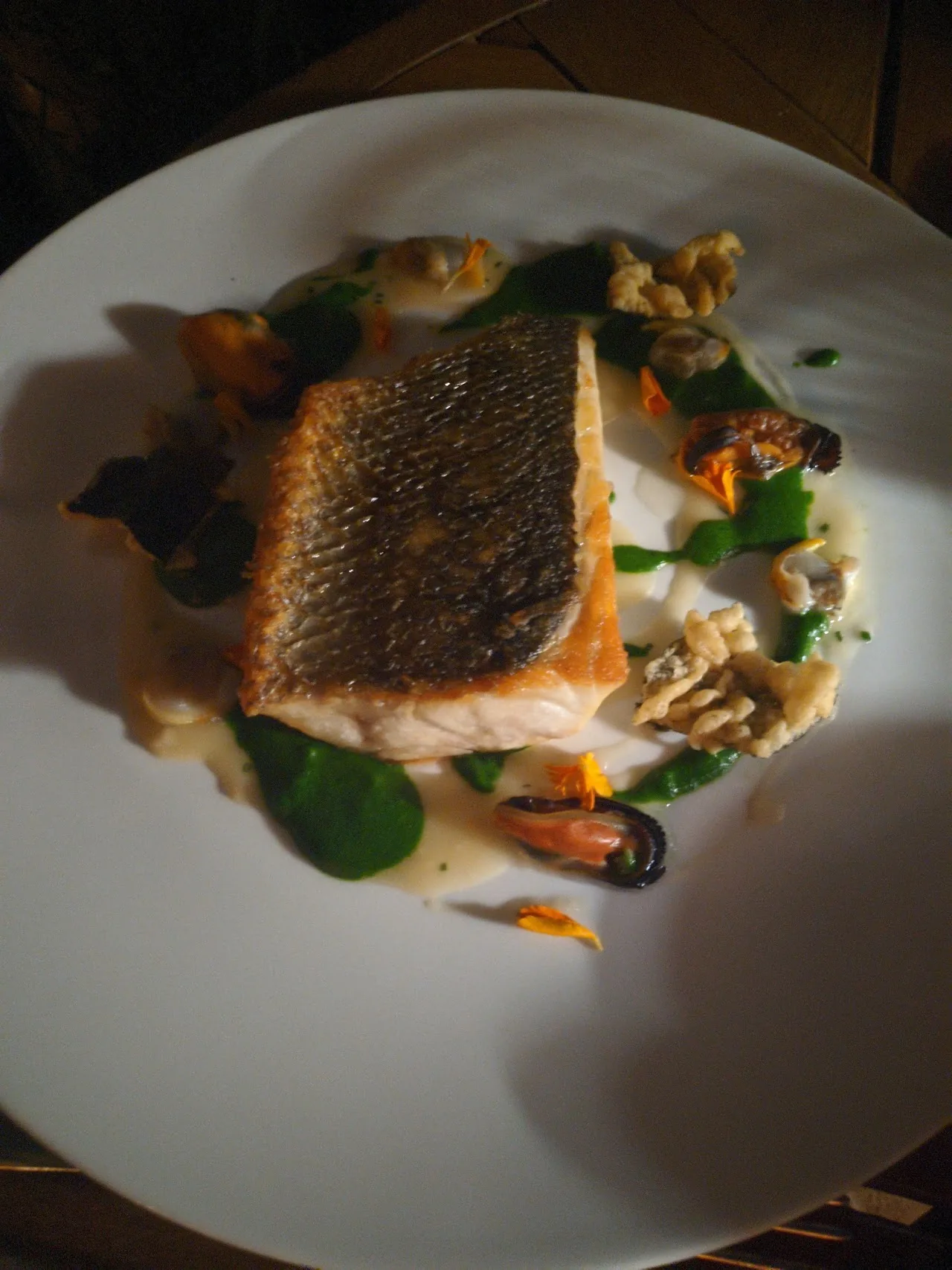 A pan-seared fish fillet with crispy skin on a bed of vegetables