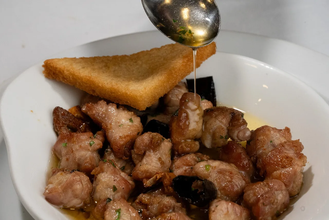 A white bowl of fried pieces of meat with a slice of toast on top