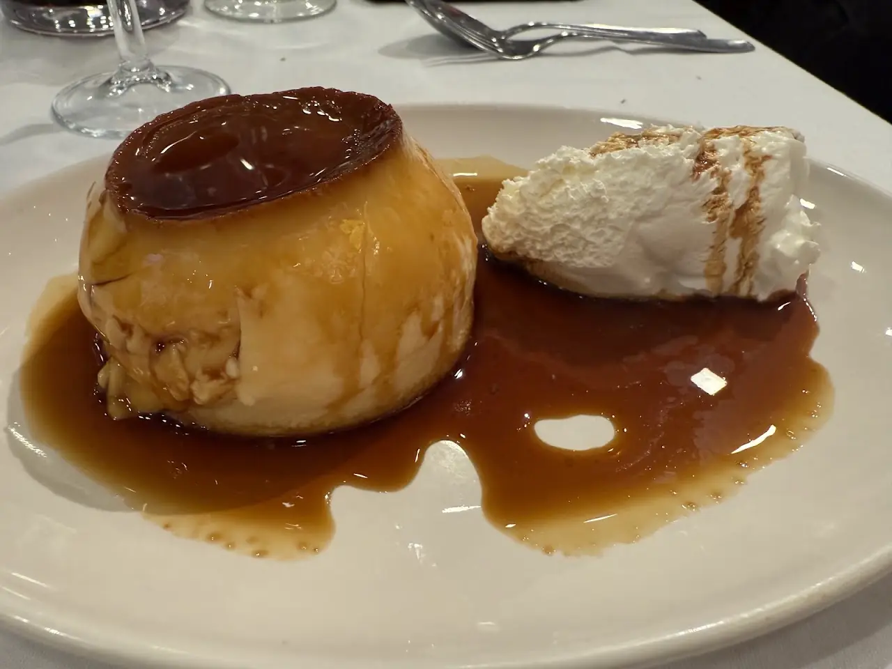 A crème caramel flan and a scoop of ice cream on a plate, both drizzled with caramel sauce