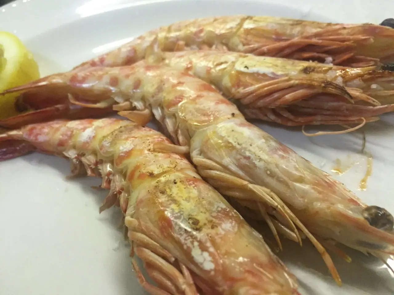 Grilled whole prawns with a lemon wedge on a white plate, Délices de France