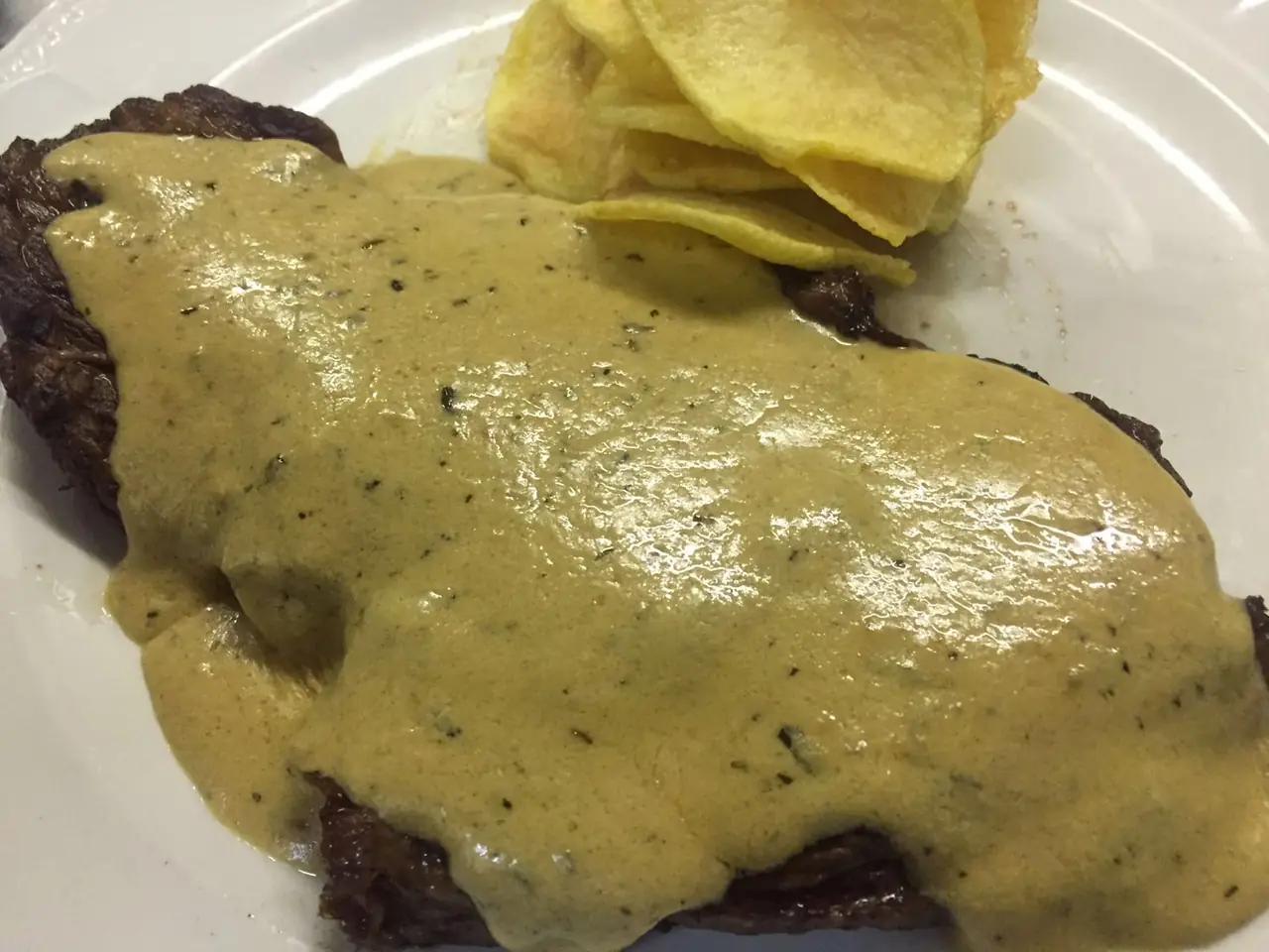 Grilled steak topped with creamy mustard sauce, served with a side of crisps, Délices de France