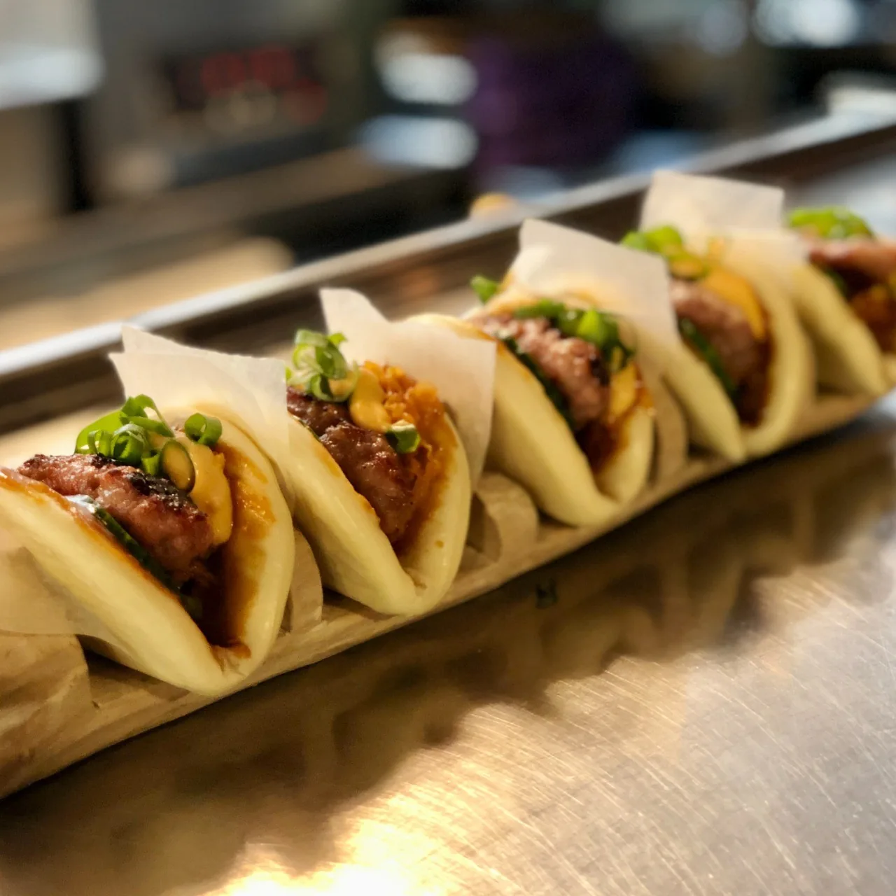 A row of steamed buns filled with meat and green garnish