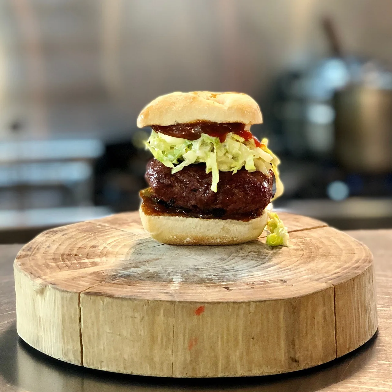 A burger with lettuce on a round wooden board