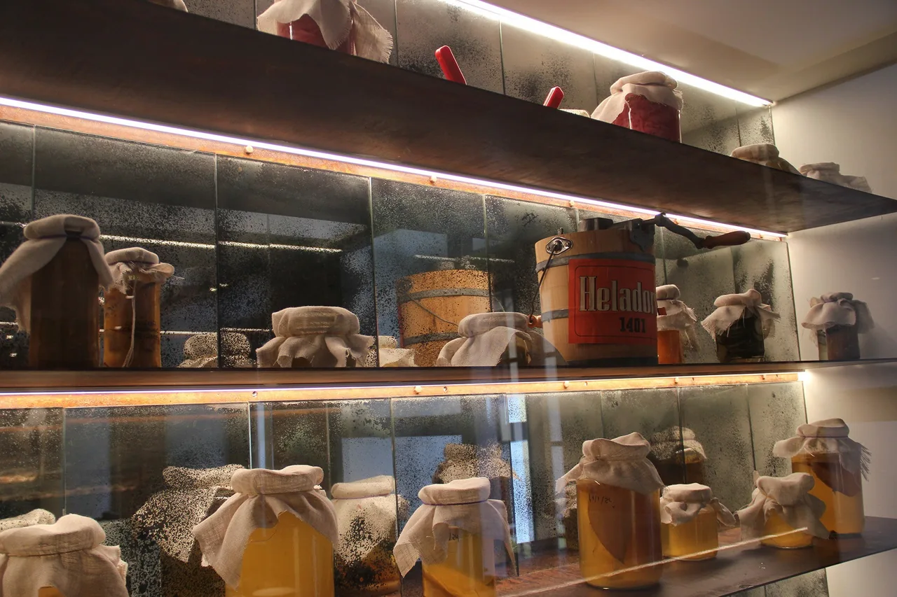 A shelf of glass jars and preserves lit by warm lights