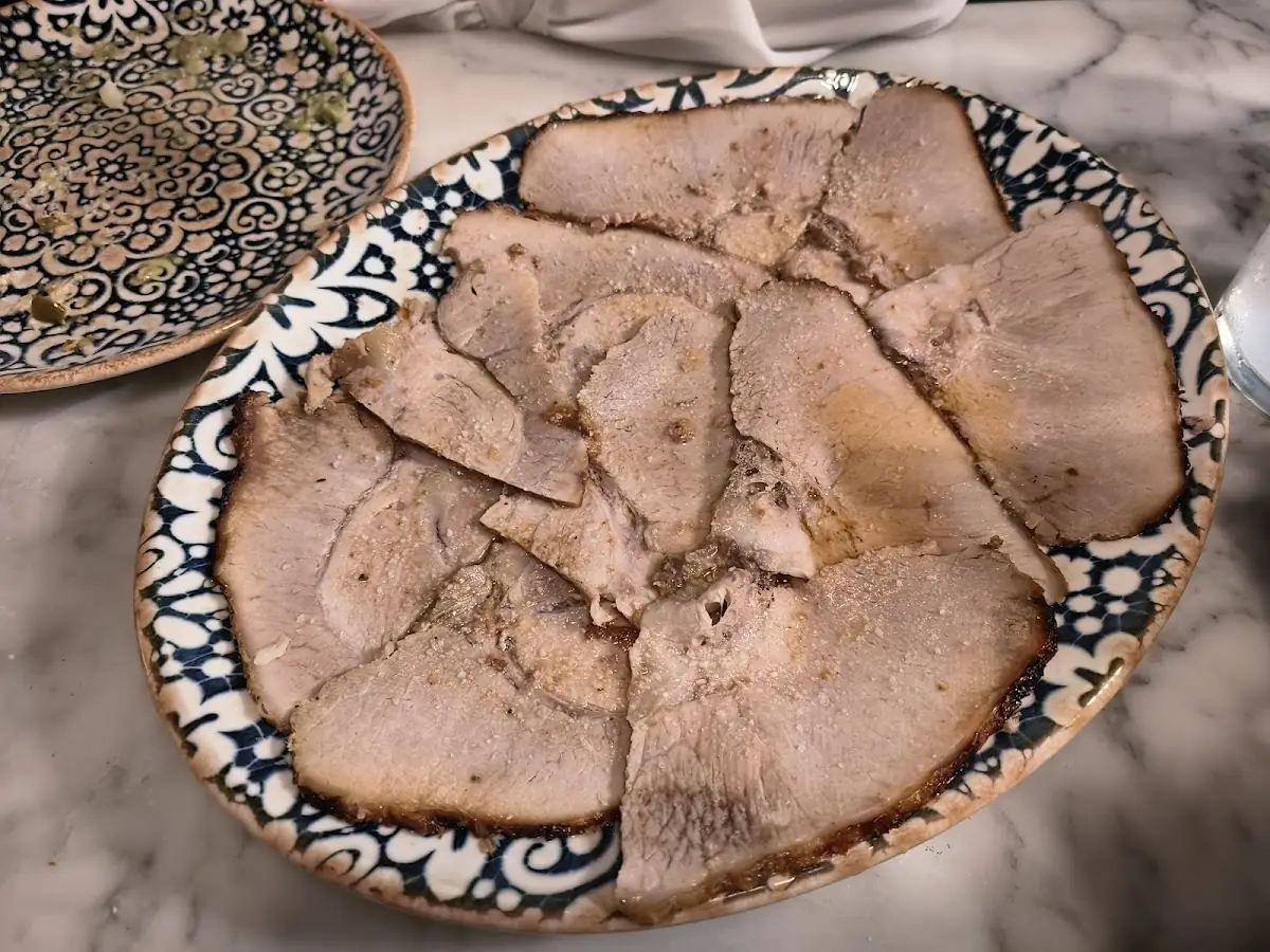 Blue-patterned plate of thin slices of roast pork on a marble table