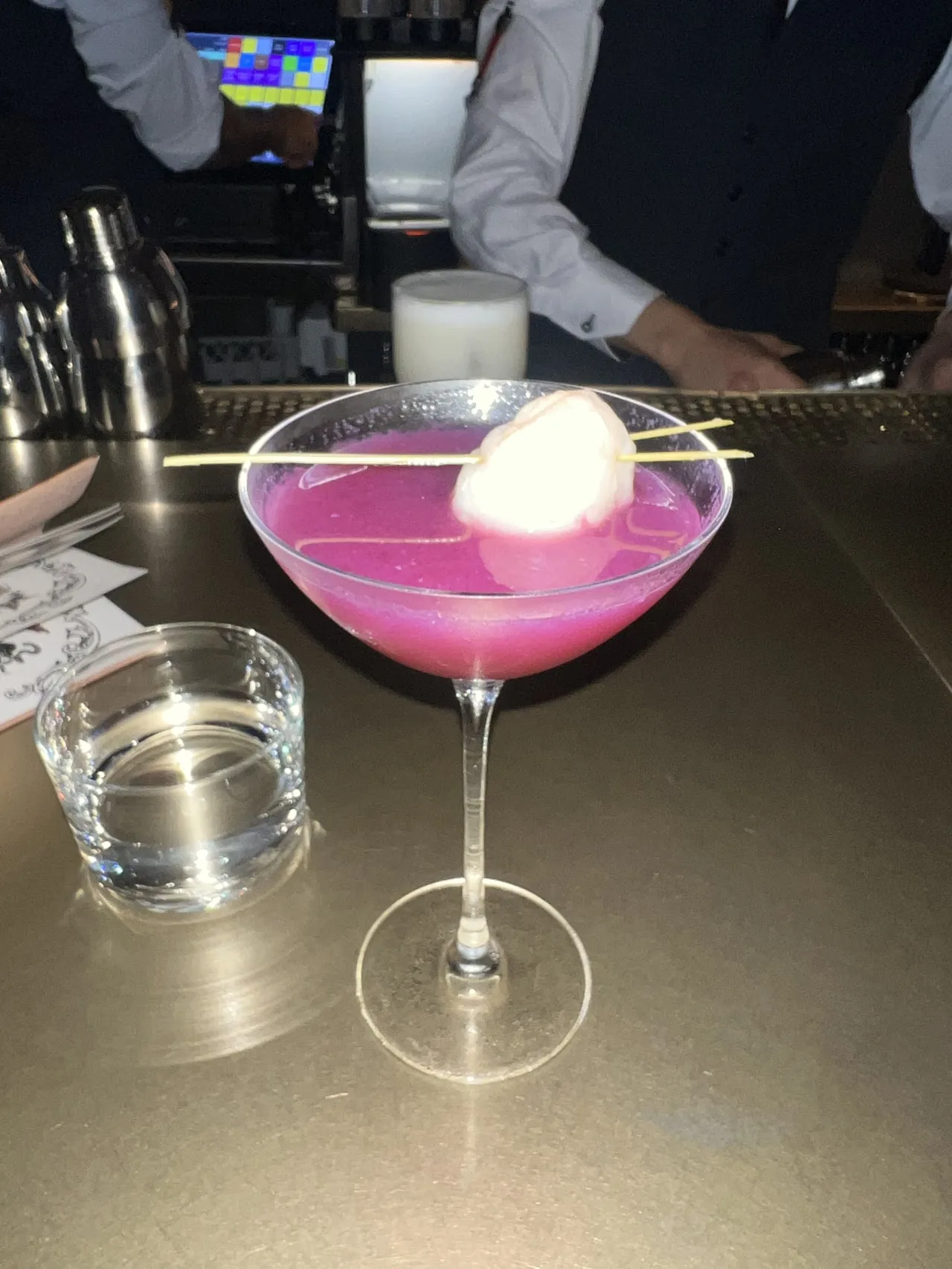 A pink cocktail topped with a scoop of white foam