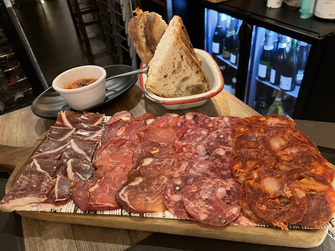 A wooden board with sliced cured meats and bread
