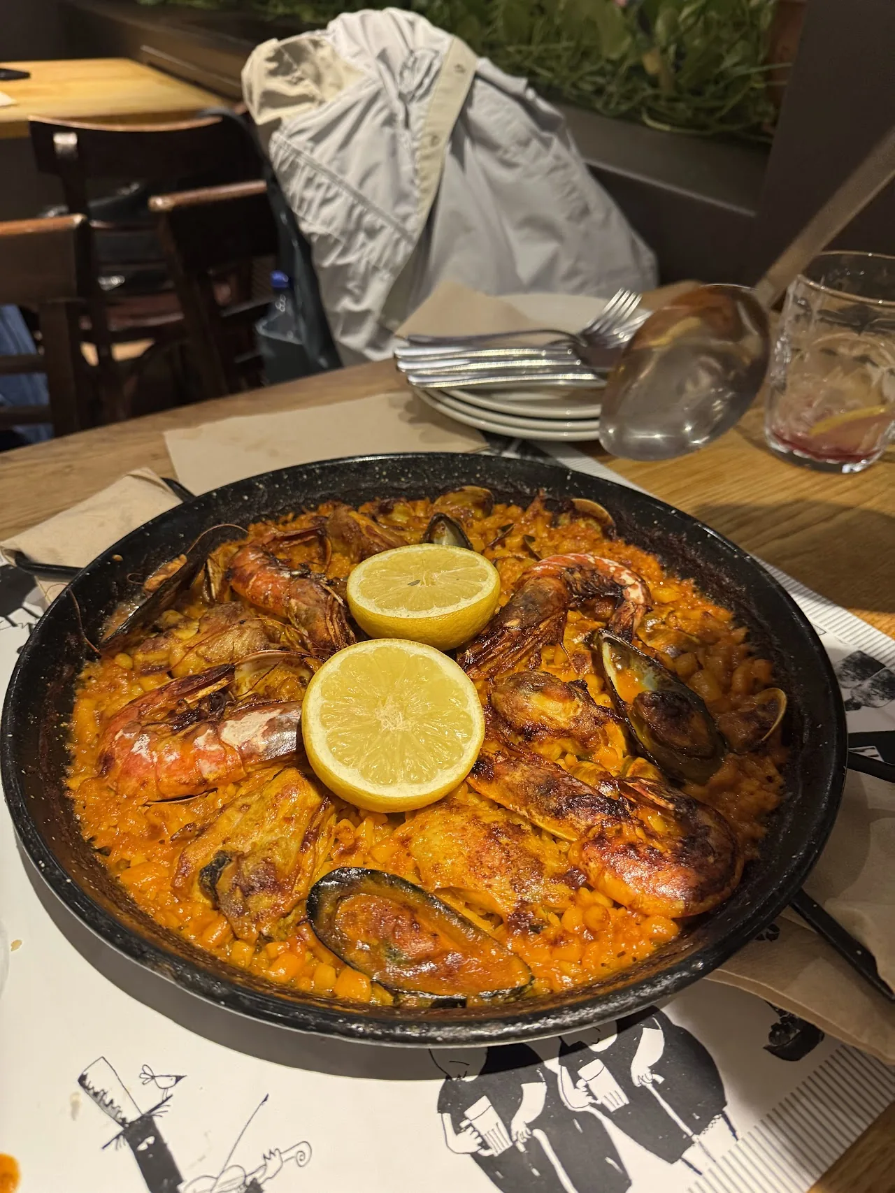 A pan of seafood paella garnished with lemon wedges