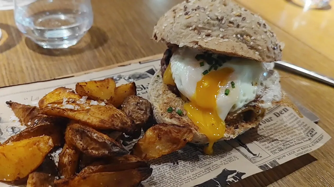 A fried egg burger served with wedge potatoes