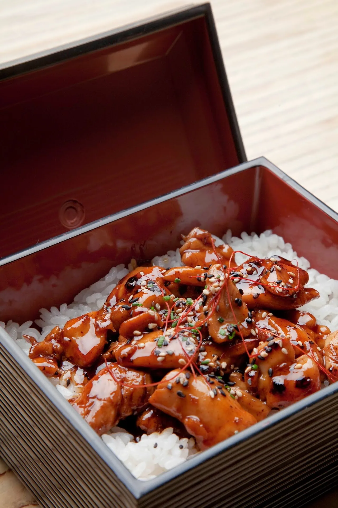 A lacquered box of rice topped with glazed meat