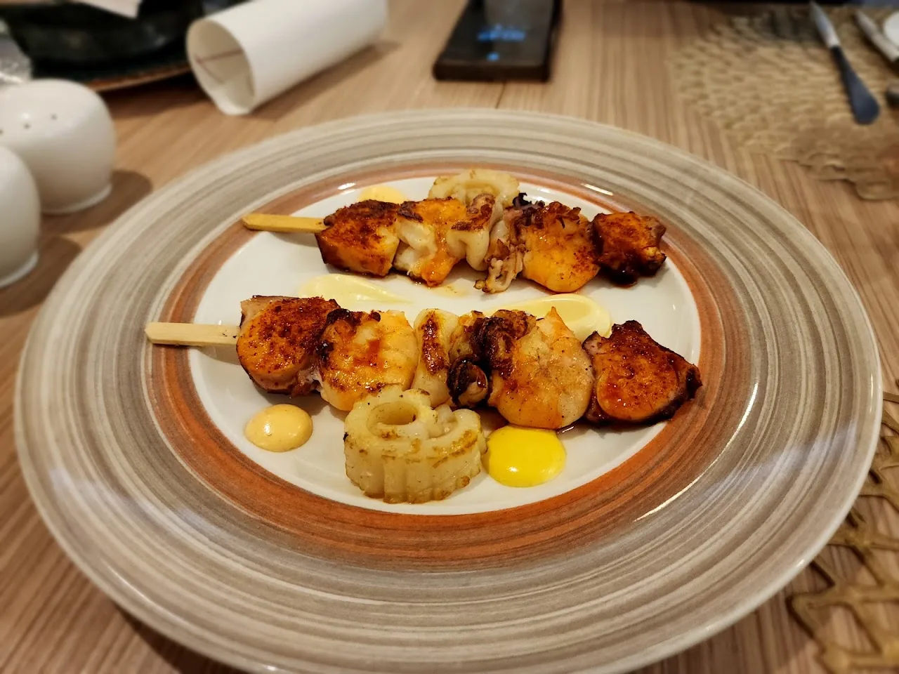 Skewered grilled meat with a dollop of sauce and a fried garnish
