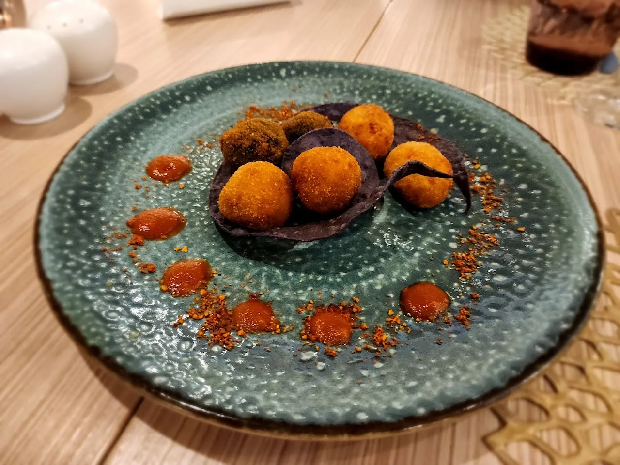 Fried croquettes on a plate with a swirl of orange sauce