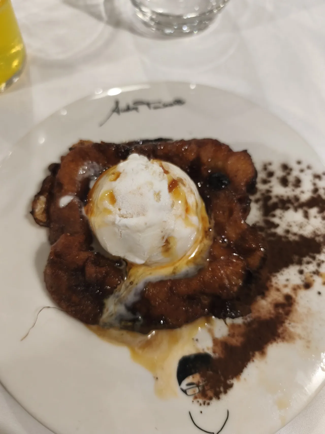 A plate with a scoop of white cream on a dark sauce and dusted with a brown topping