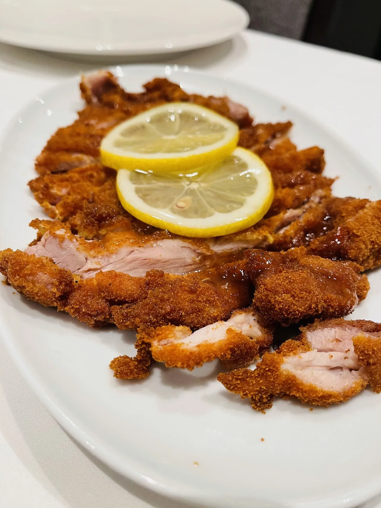 A breaded pork cutlet garnished with lemon slices